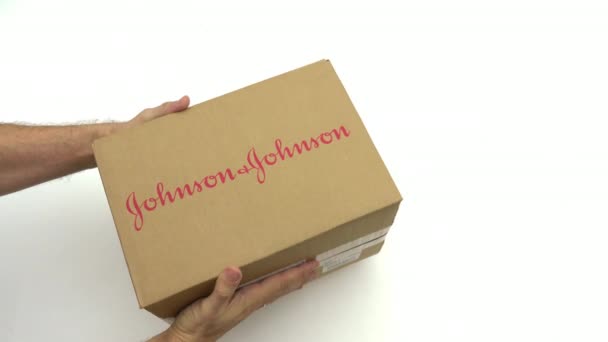 Hombre sosteniendo el cartón con el logotipo de JOHNSON Y JOHNSON. Clip editorial — Vídeos de Stock