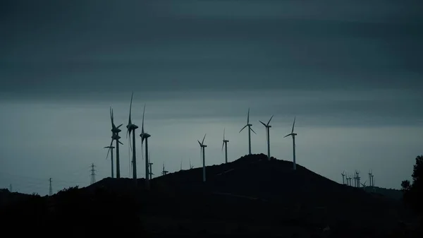 Силуэты вращающихся ветрогенераторов против голубого вечернего неба — стоковое фото