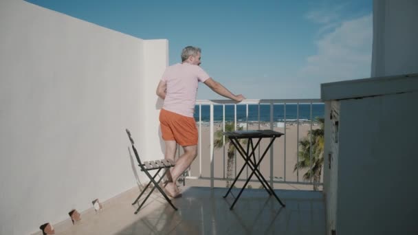 男の夏休みにホテルのテラスから海の景色を楽しんでいます。 — ストック動画