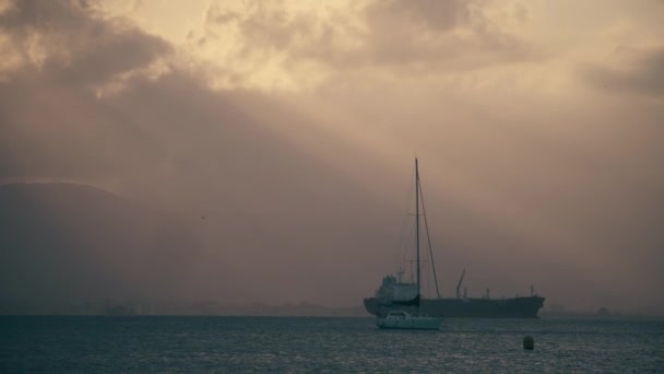 Невідомий вітрильник і вантажний корабель у морі ввечері — стокове відео