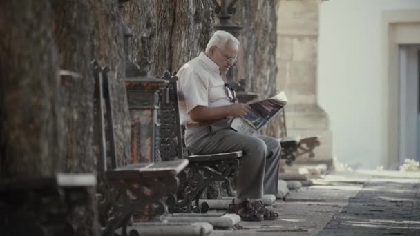 Valencia, Spanje - September 22, 2018. Oudere man zittend op een bankje en krant lezen — Stockvideo