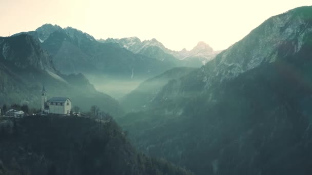 Вид с воздуха на церковь Сан-Мартино и туманную долину в северных горах Валле-ди-Кадоре, Италия — стоковое видео