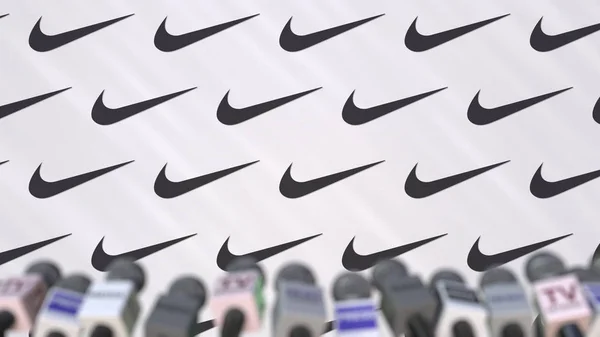 Συνέντευξη τύπου εταιρεία Nike, πατήστε τοίχος με λογότυπο και μικρόφωνα, εννοιολογική συντακτική 3d rendering — Φωτογραφία Αρχείου