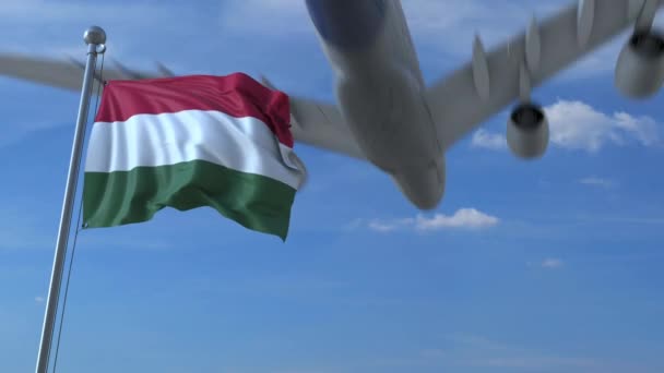 Verkehrsflugzeug landet hinter schwenkender ungarischer Flagge. Reise nach Ungarn konzeptionelle Animation — Stockvideo