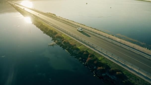 Aerial seguinte tiro de carro pequeno desconhecido dirigindo ao longo da barragem no mar à noite — Vídeo de Stock