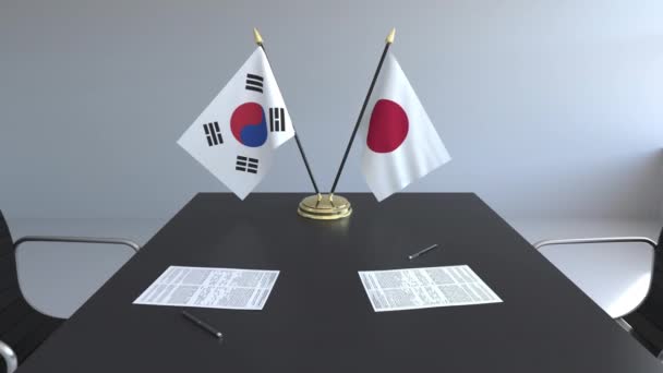 Flaggen Südkoreas und Japans und Papiere auf dem Tisch. Verhandlungen und die Unterzeichnung eines internationalen Abkommens. konzeptionelle 3D-Animation — Stockvideo