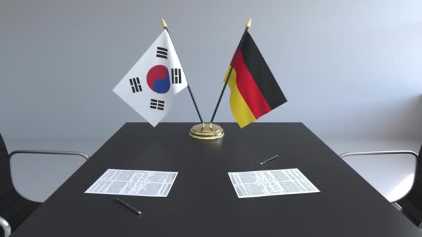Флаги Южной Кореи и Германии и бумаги на столе. Переговоры и подписание международного соглашения. Концептуальная 3D анимация — стоковое видео