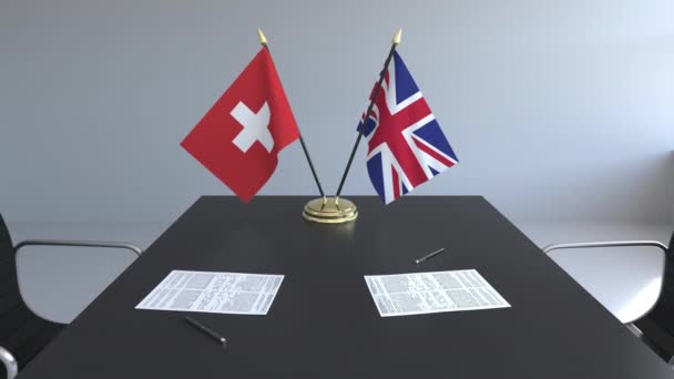 Flags of Switzerland and the United Kingdom and papers on the table. Negotiations and signing an international agreement. Conceptual 3D animation — Stock Video