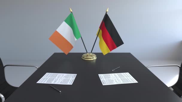 Флаги Ирландии и Германии и бумаги на столе. Переговоры и подписание международного соглашения. Концептуальная 3D анимация — стоковое видео