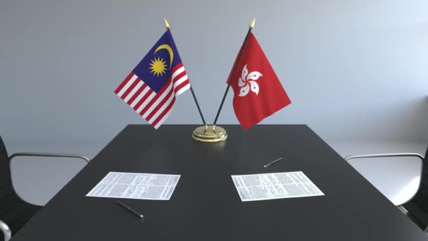 Banderas de Malasia y Hong Kong y papeles sobre la mesa. Negociaciones y firma de un acuerdo internacional. Animación 3D conceptual — Vídeo de stock