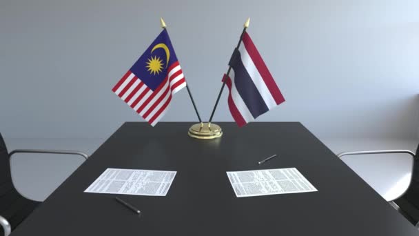 Lijst van vlaggen van Maleisië en Thailand en papieren op de tafel. Onderhandelingen en ondertekening van een internationale overeenkomst. Conceptuele 3d animatie — Stockvideo