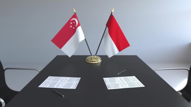 Флаги Сингапура и Индонезии и бумаги на столе. Переговоры и подписание международного соглашения. Концептуальная 3D анимация — стоковое видео