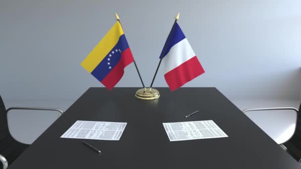 Флаги Венесуэлы и Франции и бумаги на столе. Переговоры и подписание международного соглашения. Концептуальная 3D анимация — стоковое видео
