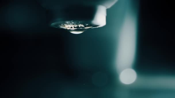 Zeitlupenaufnahme von Wassertropfen, die im dunklen Badezimmer aus dem Wasserhahn fallen — Stockvideo