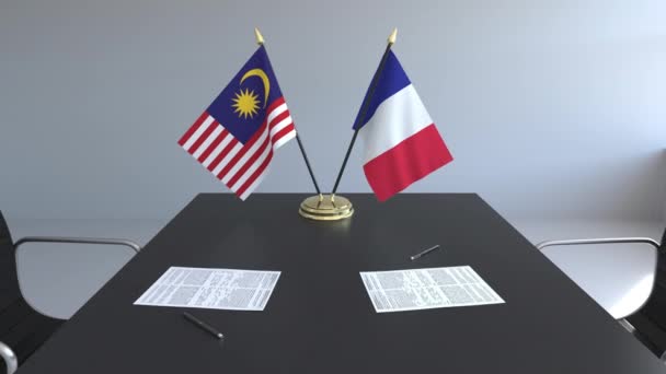 Флаги Малайзии и Франции и бумаги на столе. Переговоры и подписание международного соглашения. Концептуальная 3D анимация — стоковое видео