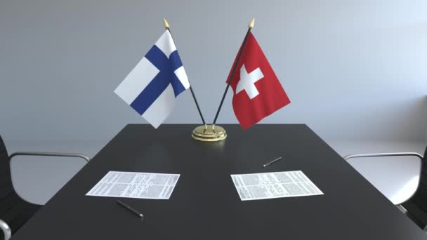 Флаги Финляндии и Швейцарии и бумаги на столе. Переговоры и подписание международного соглашения. Концептуальная 3D анимация — стоковое видео