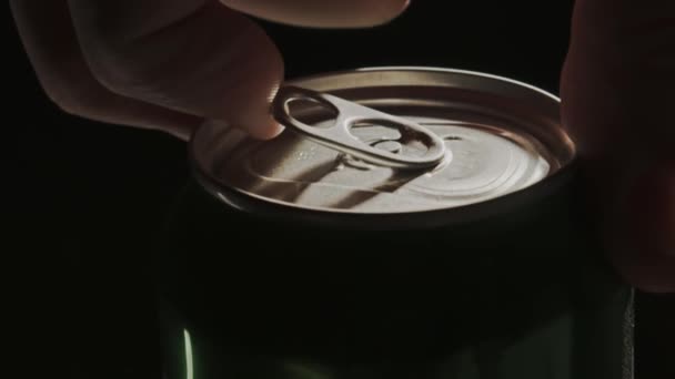 Человек открывает алюминиевую банку пива на черном фоне — стоковое видео