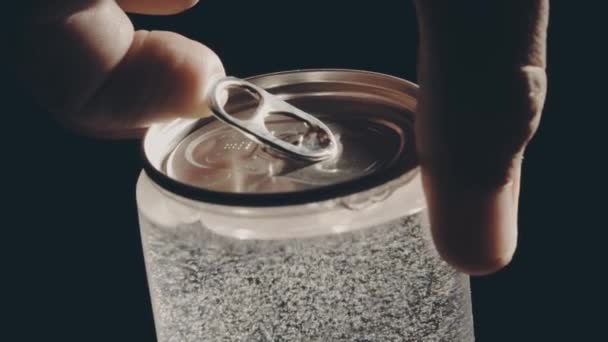 Man opens the transparent beverage can against black background — Stock Video