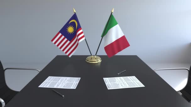 Banderas de Malasia e Italia y papeles sobre la mesa. Negociaciones y firma de un acuerdo internacional. Animación 3D conceptual — Vídeo de stock
