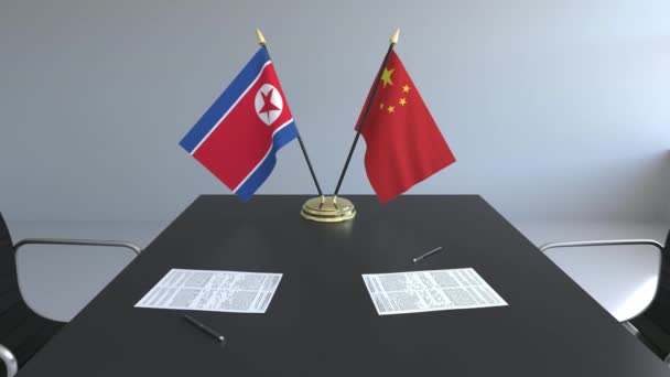 Flaggen Nordkoreas und Chinas und Papiere auf dem Tisch. Verhandlungen und die Unterzeichnung eines internationalen Abkommens. konzeptionelle 3D-Animation — Stockvideo