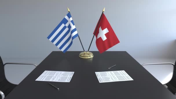 Флаги Греции и Швейцарии и бумаги на столе. Переговоры и подписание международного соглашения. Концептуальная 3D анимация — стоковое видео