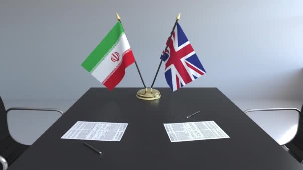 Флаги Ирана и Великобритании и бумаги на столе. Переговоры и подписание международного соглашения. Концептуальная 3D анимация — стоковое видео