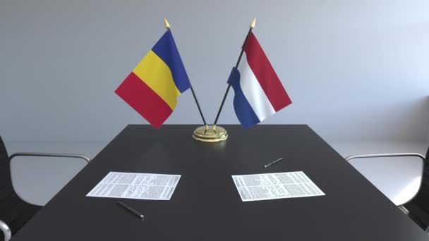 Флаги Румынии и Нидерландов и бумаги на столе. Переговоры и подписание международного соглашения. Концептуальная 3D анимация — стоковое видео