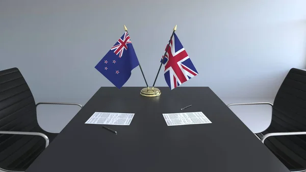 Flaggen von Neuseeland und des vereinigten Königreichs und Papiere auf dem Tisch. Verhandlungen und die Unterzeichnung eines internationalen Abkommens. konzeptionelles 3D-Rendering — Stockfoto