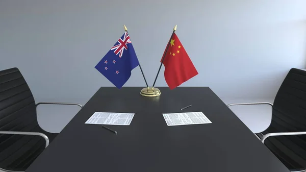 Flaggen von Neuseeland und China und Papiere auf dem Tisch. Verhandlungen und die Unterzeichnung eines internationalen Abkommens. konzeptionelles 3D-Rendering — Stockfoto