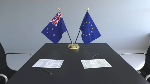 Flaggen von Neuseeland und der Europäischen Union und Papiere auf dem Tisch. Verhandlungen und die Unterzeichnung eines internationalen Abkommens. konzeptionelles 3D-Rendering — Stockfoto