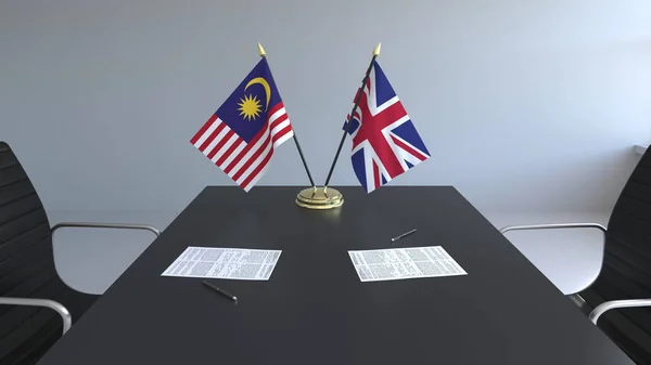 Flaggor av Malaysia och Storbritannien och papper på bordet. Förhandlingarna och underteckna internationella avtal. Konceptuell 3d-rendering — Stockfoto
