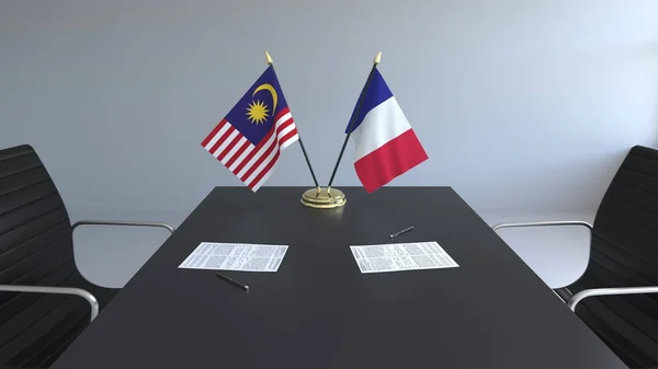 Flaggen von Malaysia und Frankreich und Papiere auf dem Tisch. Verhandlungen und die Unterzeichnung eines internationalen Abkommens. konzeptionelles 3D-Rendering — Stockfoto