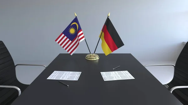 Flaggor av Malaysia och Tyskland och papper på bordet. Förhandlingarna och underteckna internationella avtal. Konceptuell 3d-rendering — Stockfoto
