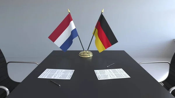 Banderas de Holanda y Alemania y documentos sobre la mesa. Negociaciones y firma de un acuerdo internacional. Renderizado 3D conceptual —  Fotos de Stock
