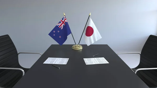 Flaggen von Neuseeland und Japan und Papiere auf dem Tisch. Verhandlungen und die Unterzeichnung eines internationalen Abkommens. konzeptionelles 3D-Rendering — Stockfoto
