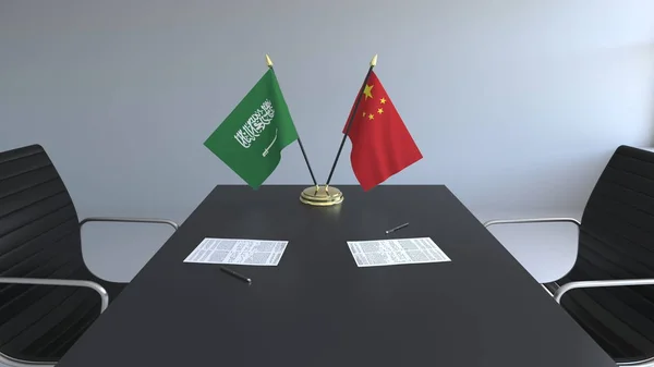 Flaggen von Saudi-Arabien und China und Papiere auf dem Tisch. Verhandlungen und die Unterzeichnung eines internationalen Abkommens. konzeptionelles 3D-Rendering — Stockfoto