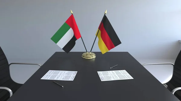 Bandeiras dos Emirados Árabes Unidos e da Alemanha e papéis na mesa. Negociações e assinatura de um acordo internacional. Renderização 3D conceitual — Fotografia de Stock