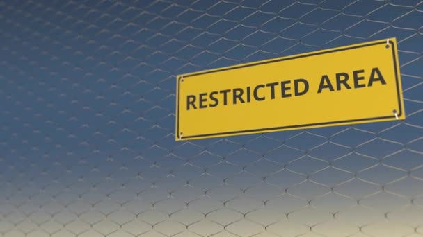 RESTRICTED AREA text on the yellow plate on a mesh wire fence against blue sky. 3D animation — Stock Video