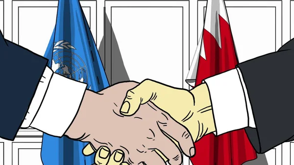 Бизнесмены или политики пожимают руки флагам ООН и Бахрейна. Официальная редакционная иллюстрация встречи или сотрудничества — стоковое фото