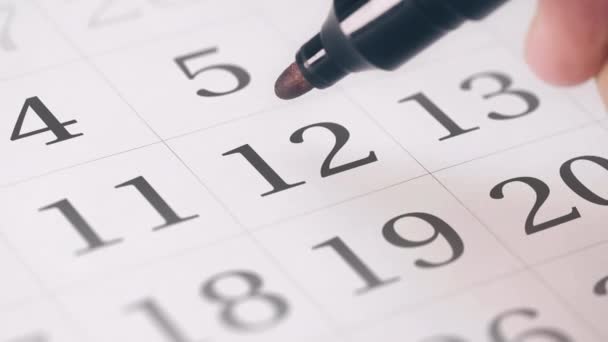 Marcando el duodécimo día de un mes en el calendario con un marcador rojo — Vídeos de Stock