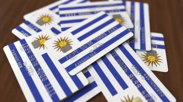 Pile of credit cards with flag of Uruguay. Uruguayan banking system conceptual 3D animation — Stock Video