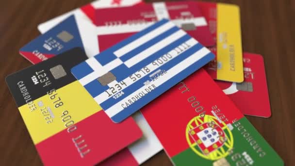 Viele Kreditkarten mit verschiedenen Flaggen, hervorgehobene Bankkarte mit griechischer Flagge — Stockvideo