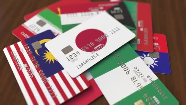 Veel creditcards met verschillende vlaggen, benadrukte bankkaart met vlag van Japan — Stockvideo