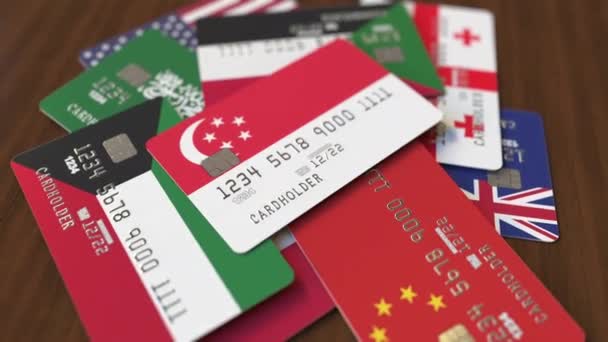 Muchas tarjetas de crédito con diferentes banderas, hizo hincapié en la tarjeta bancaria con bandera de Singapur — Vídeo de stock
