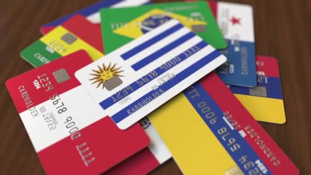 Veel creditcards met verschillende vlaggen, benadrukte bankkaart met vlag van Uruguay — Stockvideo