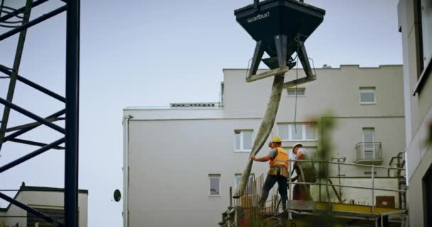 WARSAW, POLONIA - 24 MAGGIO 2019. Due costruttori lavorano con dispenser di cemento in un cantiere edile — Video Stock