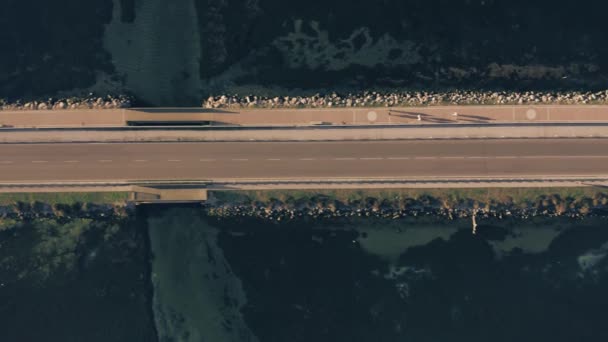 夕方に海のダムに沿って移動する車、人やサイクリストの空中トップダウンショット。オルベテッロ(イタリア) — ストック動画