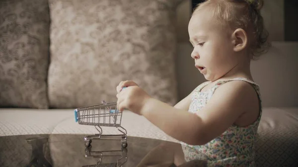 Menina bebê brincando com carrinho de compras de brinquedo em casa — Fotografia de Stock