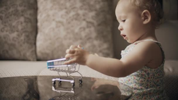 Baby girl playing with toy shopping trolley at home — Stock Video