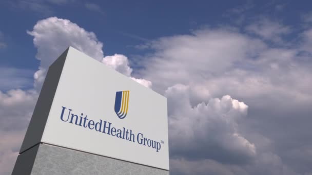 Логотип UNITEDHEALTH GROUP на стенде против облачного неба, редакционная анимация — стоковое видео
